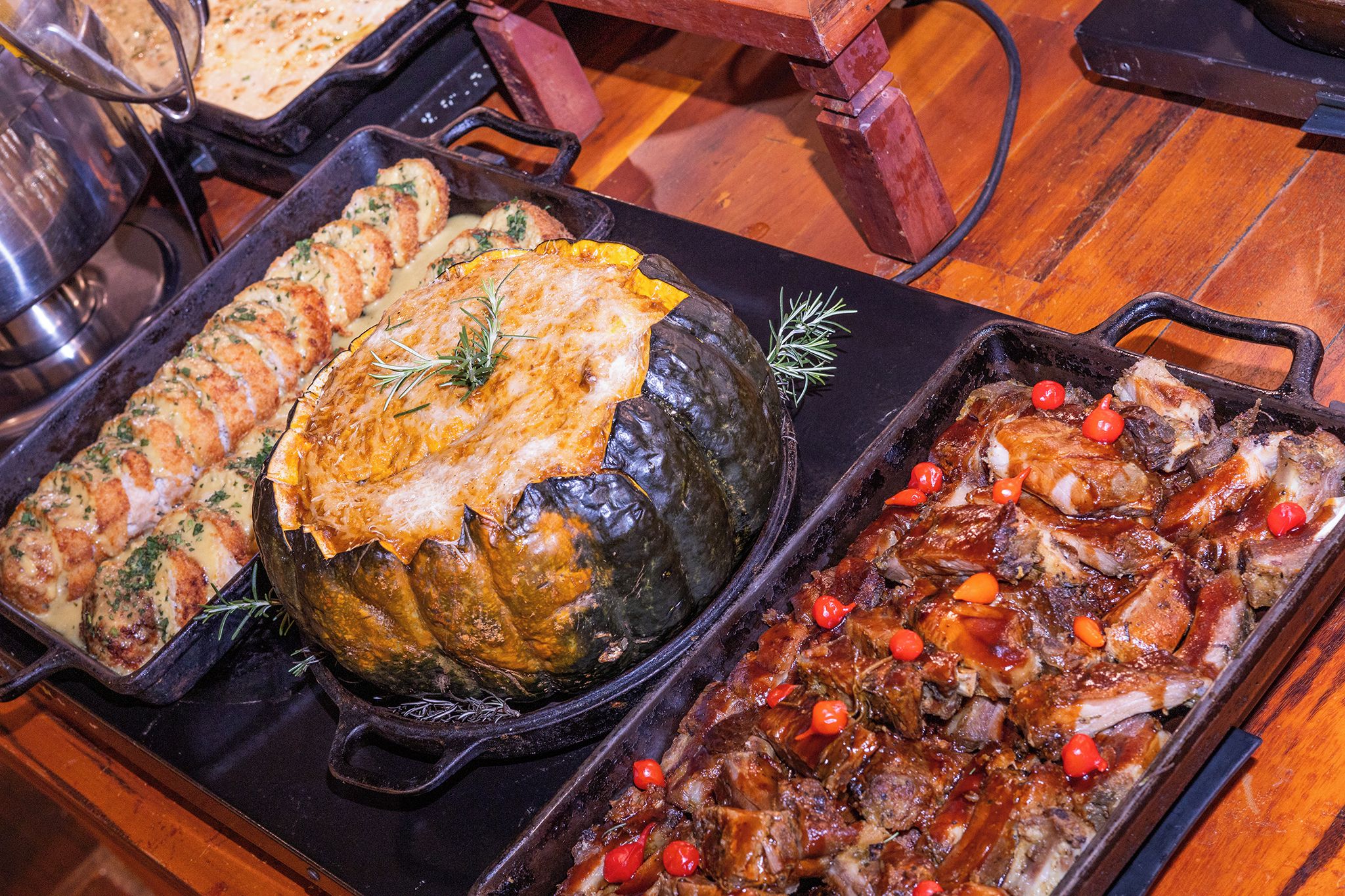 A variety of dishes in cast iron skillets, including a roasted eggplant, a baked dish with a golden crust, and a meat dish with red peppers.