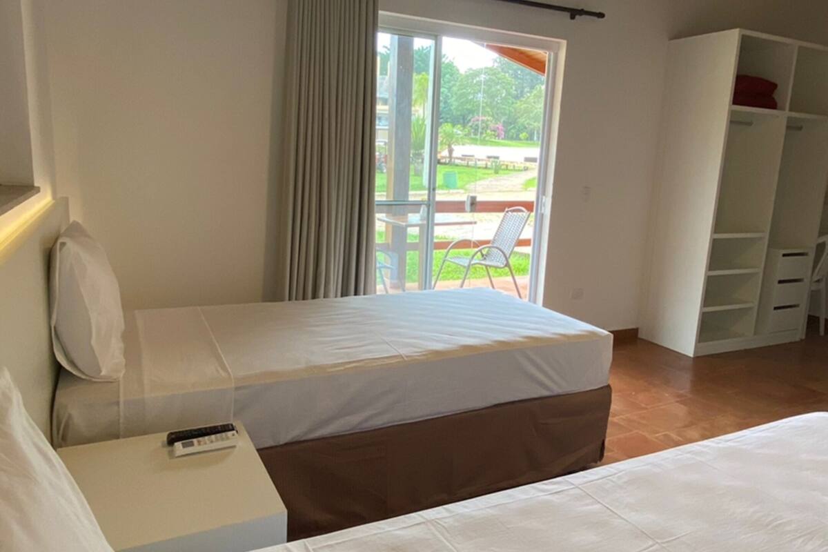 Une chambre à coucher comprenant un lit, une table de chevet, une armoire et une vue sur l’extérieur par une fenêtre.