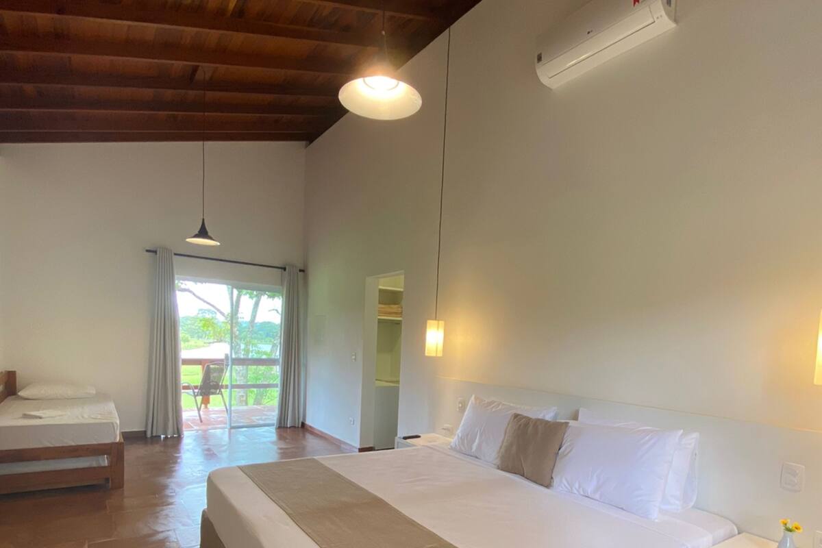 Une chambre spacieuse avec un grand lit, un plafond en bois et une vue sur l’extérieur.