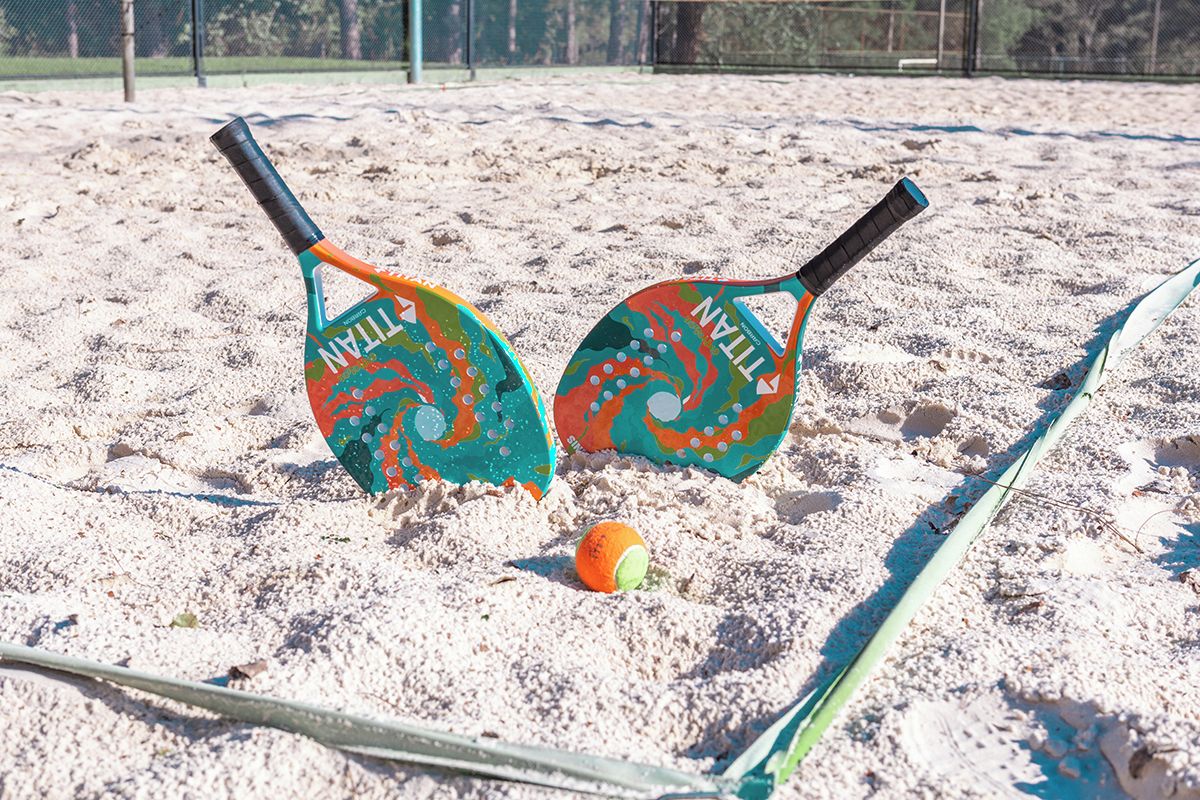 Duas pranchas de paddle em uma superfície arenosa, com uma bola no meio.