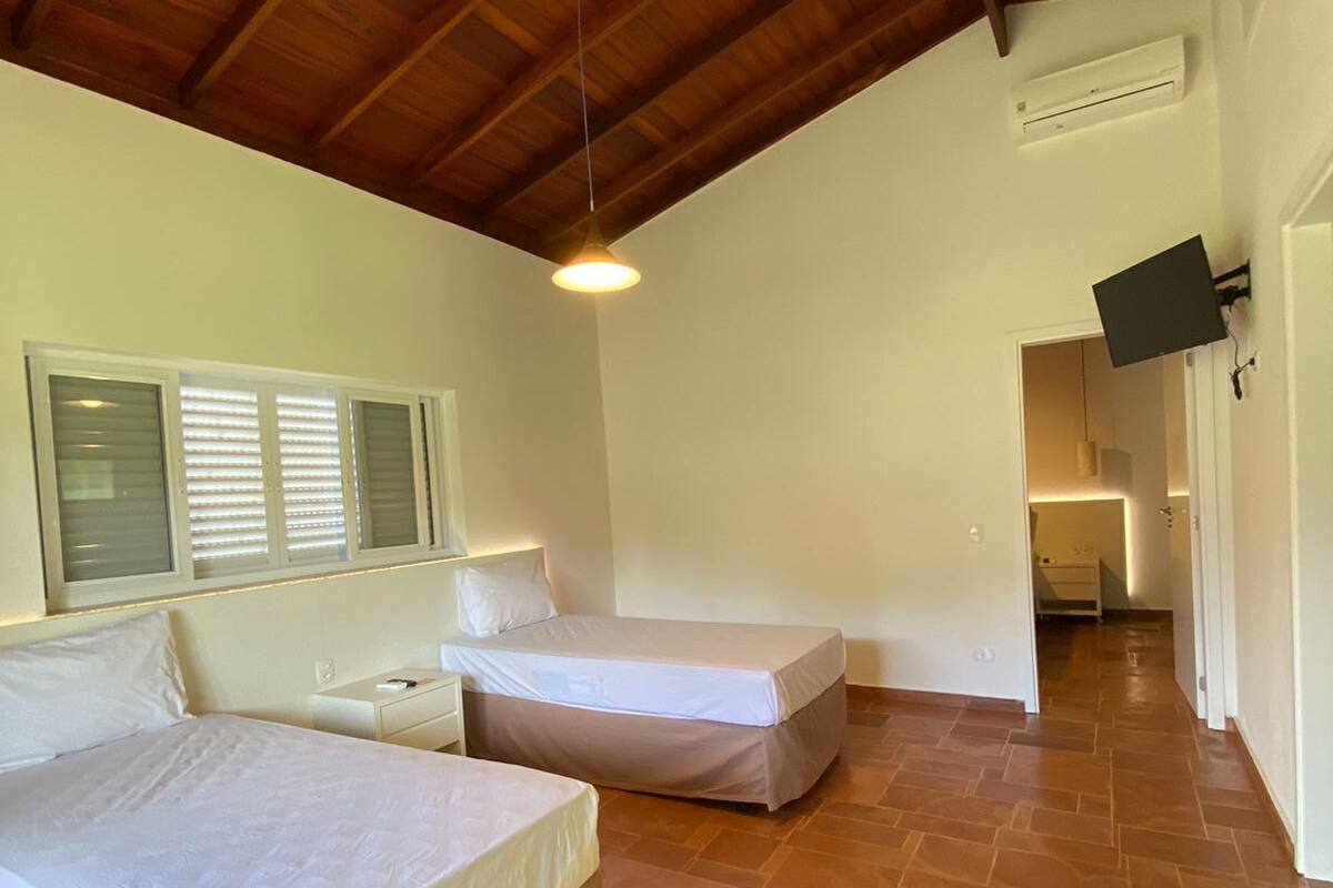 Une chambre avec deux lits, un plafond en bois et un sol carrelé.