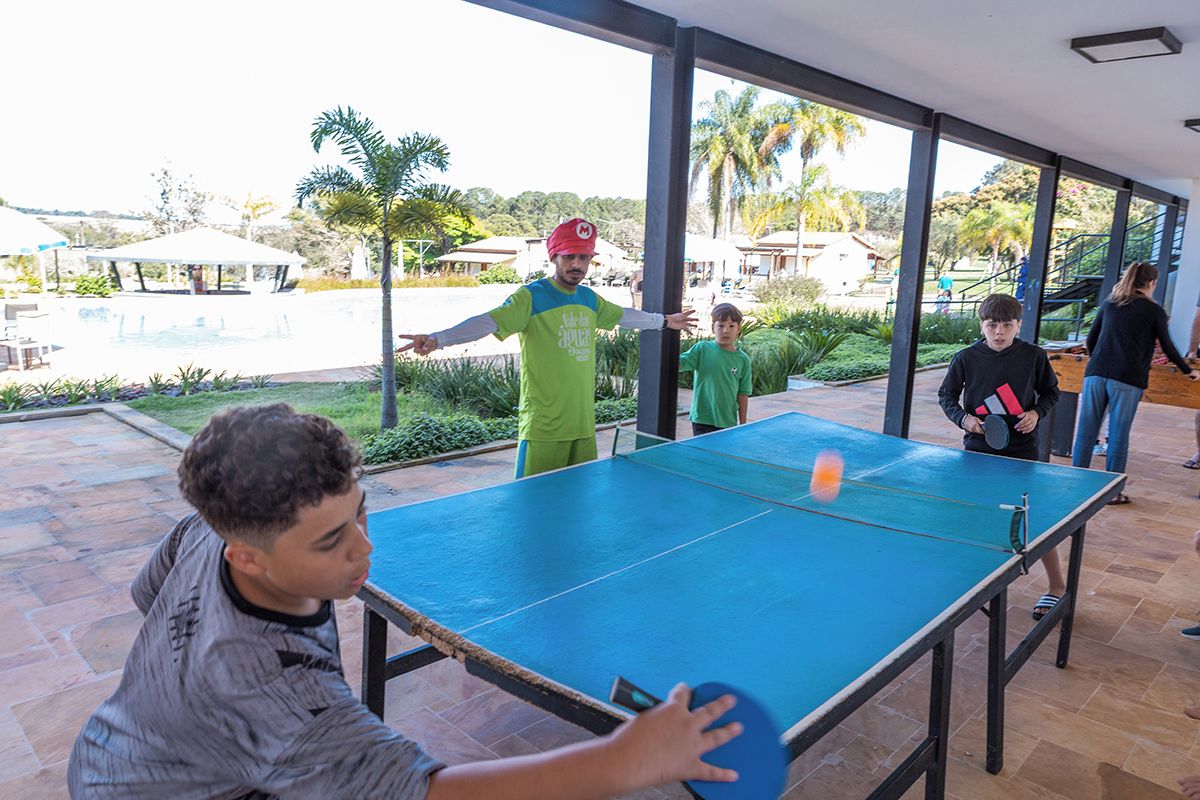 Una instalación de tenis de mesa al aire libre con una red, rodeada de gente.