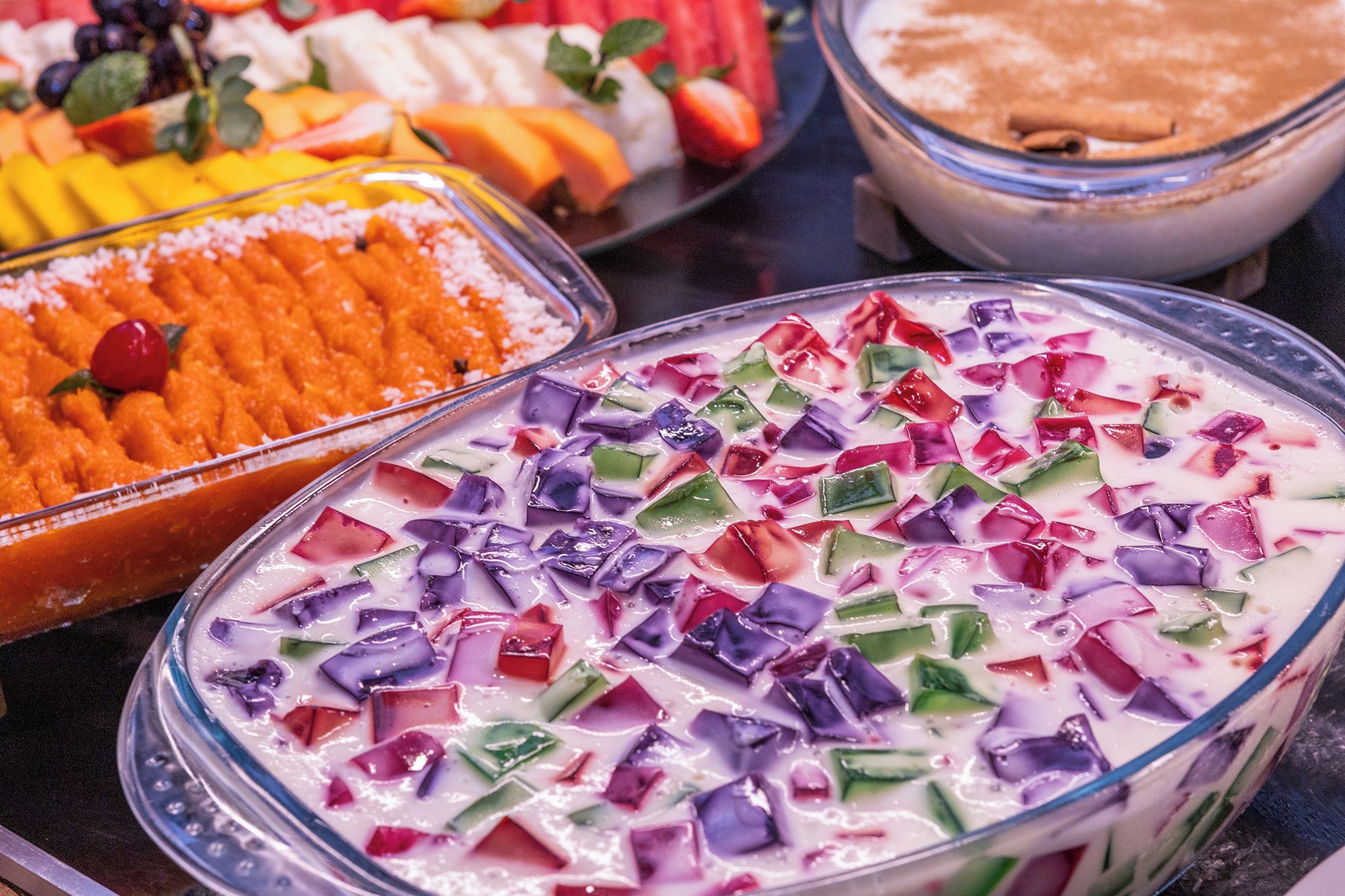 A variety of dishes including a bowl of colorful fruit salad and a dish with orange chunks.