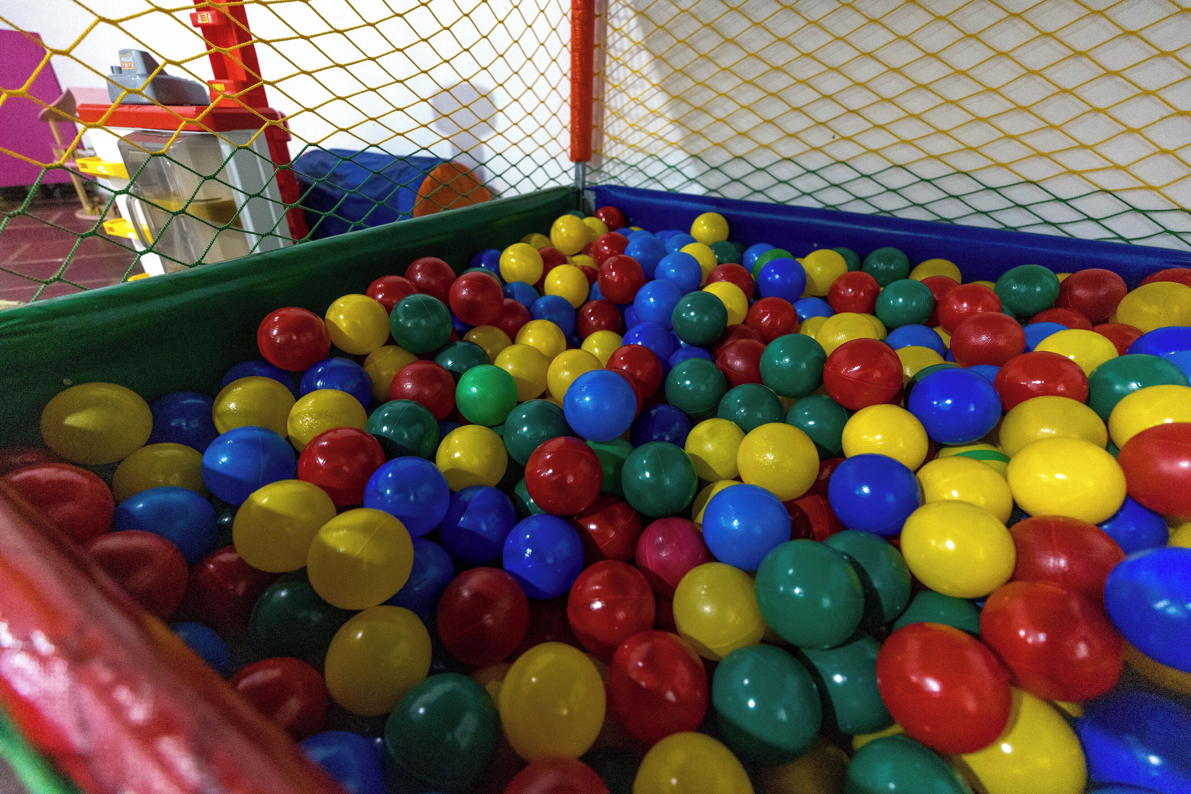 A play area with a netted enclosure filled with multicolored plastic balls.
