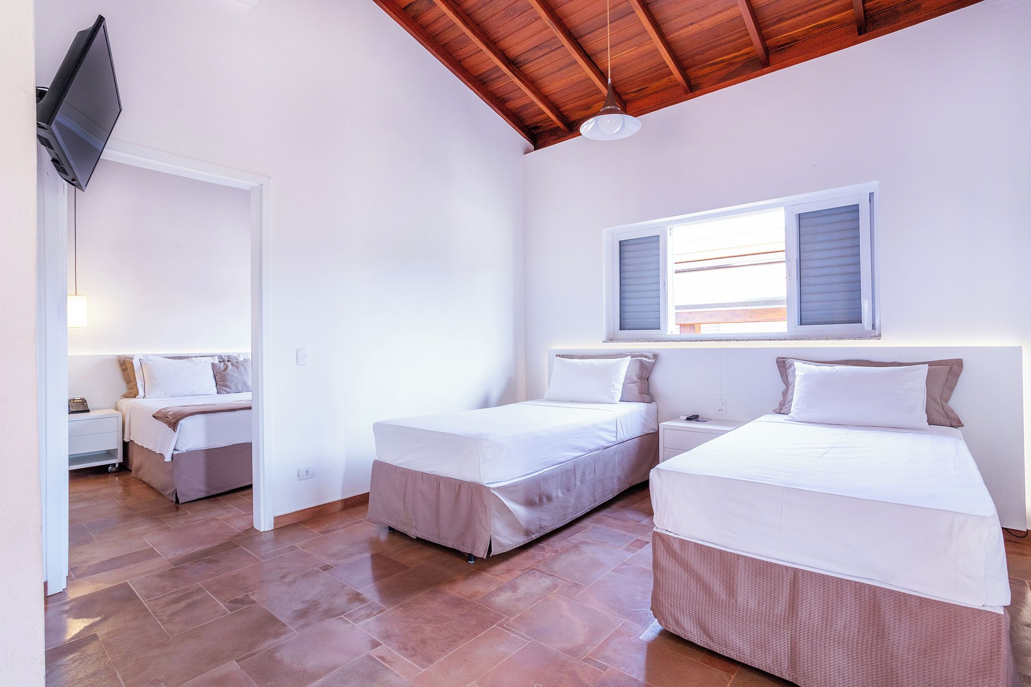 A bedroom with two beds, a desk, and a television.