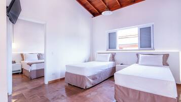 A bedroom with two beds, a desk, and a television.