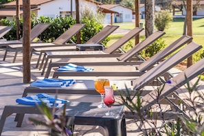 A poolside area with lounge chairs and a table with drinks.
