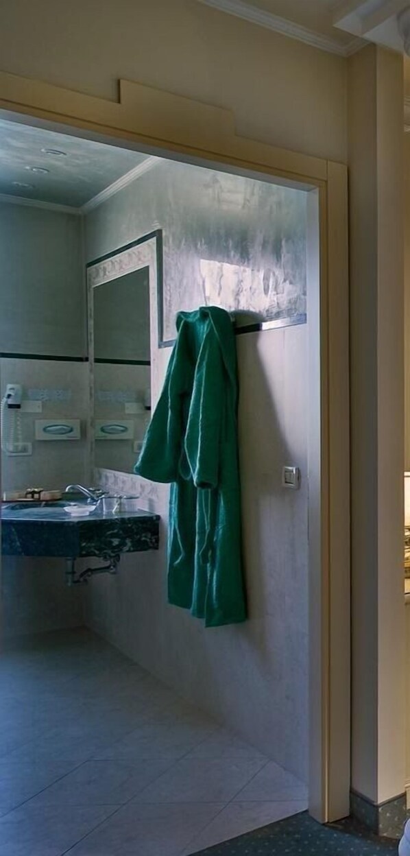A bathroom with a sink, mirror, and a green towel hanging on the wall. - Hotel Quisisana (Abano Terme)