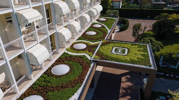 A hotel with multiple balconies, a rooftop garden with circular planters, and a paved walkway. - Hotel Quisisana (Abano Terme)