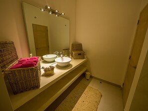 Ein Badezimmer mit zwei Waschbecken, einem großen Spiegel, Korbwannen und einem rosa Handtuch.