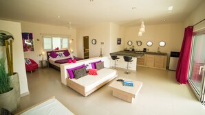 A modern living room with a sofa, coffee table, and a kitchen area with a bar. - Villas Agua Dulce - Loft Panaema (Sosúa)
