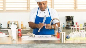 A chef in a kitchen with a sink, cutting board, and various kitchen utensils. - Villas Agua Dulce - Loft Panaema (Sosúa)