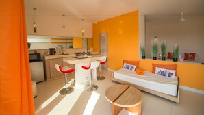 Un apartamento moderno con kitchenette, una zona de comedor con taburetes de bar, una cama con vistas y una pequeña mesa redonda.