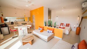 Una habitación de hotel moderna con kitchenette, sofá cama, zona de comedor y baño.