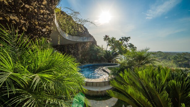 Una piscina rodeada de vegetación exuberante y un acantilado.