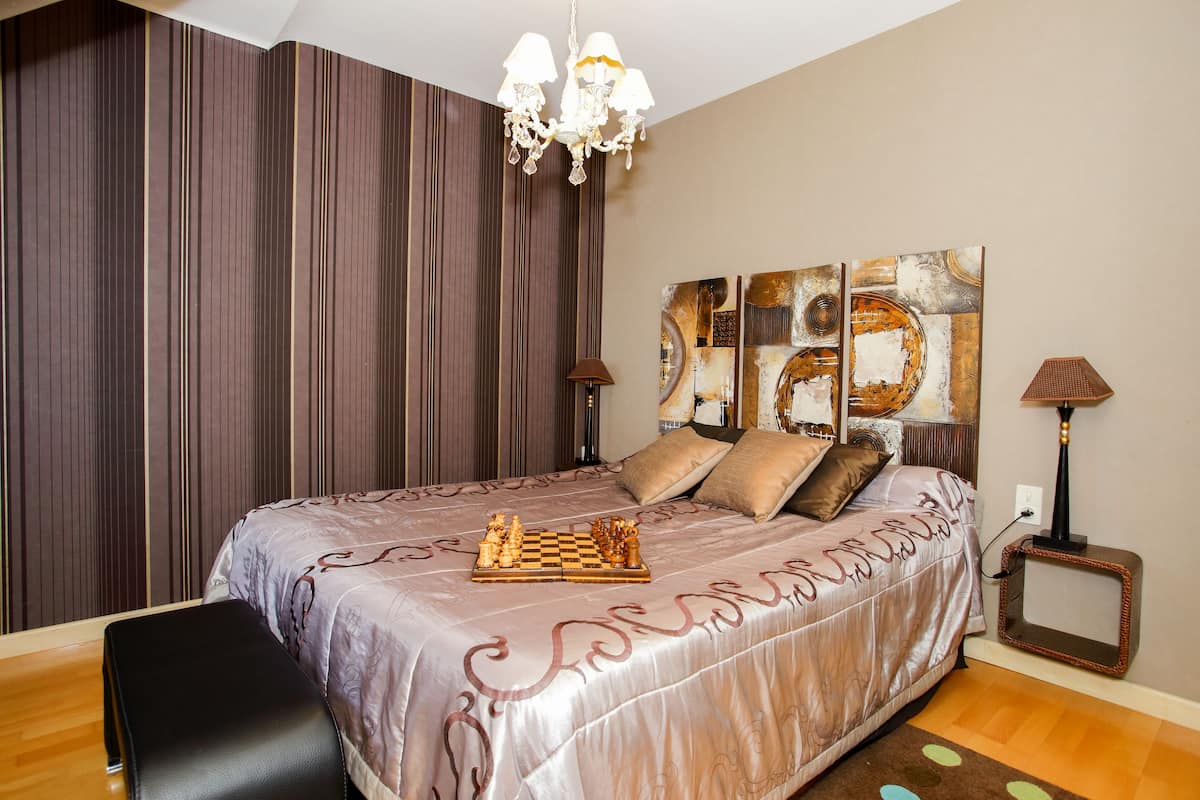 Ein Schlafzimmer mit einem großen Bett, einer Chandelier, einem Fernseher und einem Schachbrett auf dem Bett.