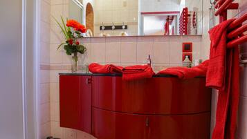 A bathroom with a red vanity, a mirror, and a red towel rack.