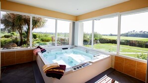 Une salle de bain moderne avec une grande baignoire, de grandes fenêtres et une vue sur l’extérieur.