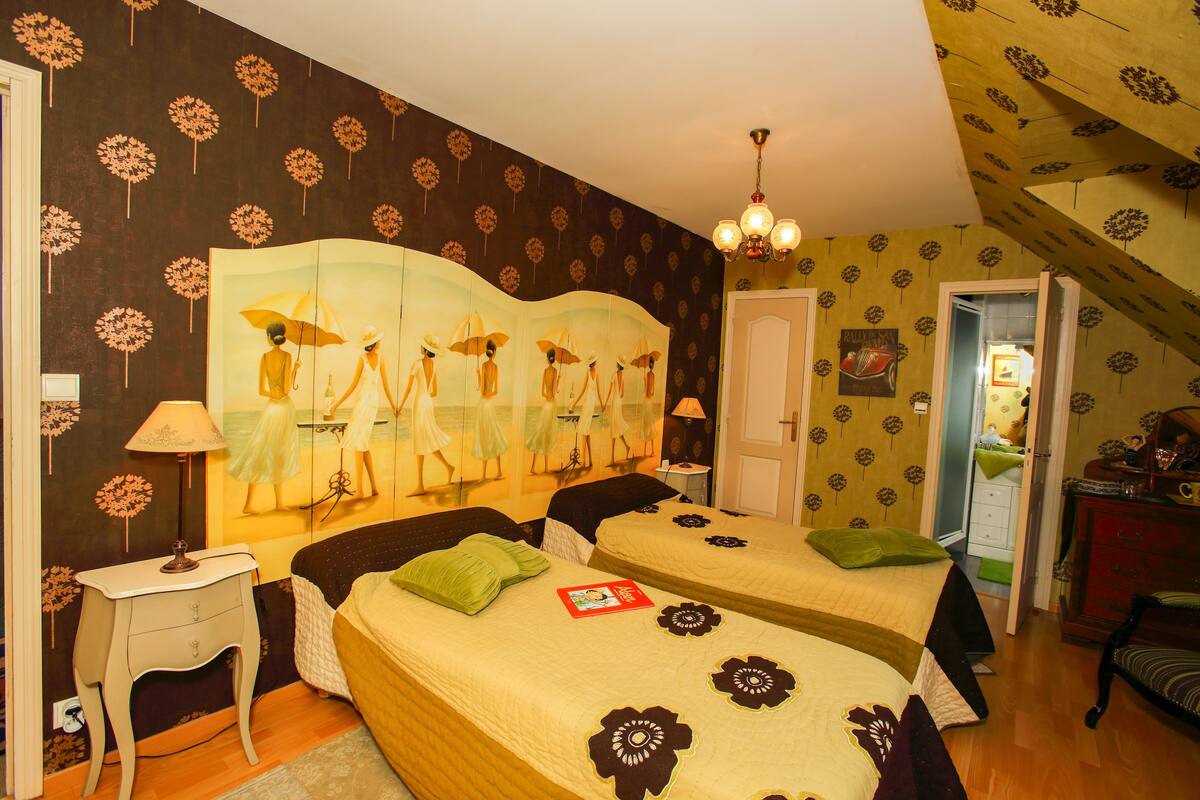 Ein Schlafzimmer mit zwei Betten, einem Nachttisch, einer Lampe und Wandbild.