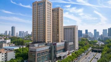 A high-rise building with multiple floors, surrounded by other buildings and a busy road with vehicles.