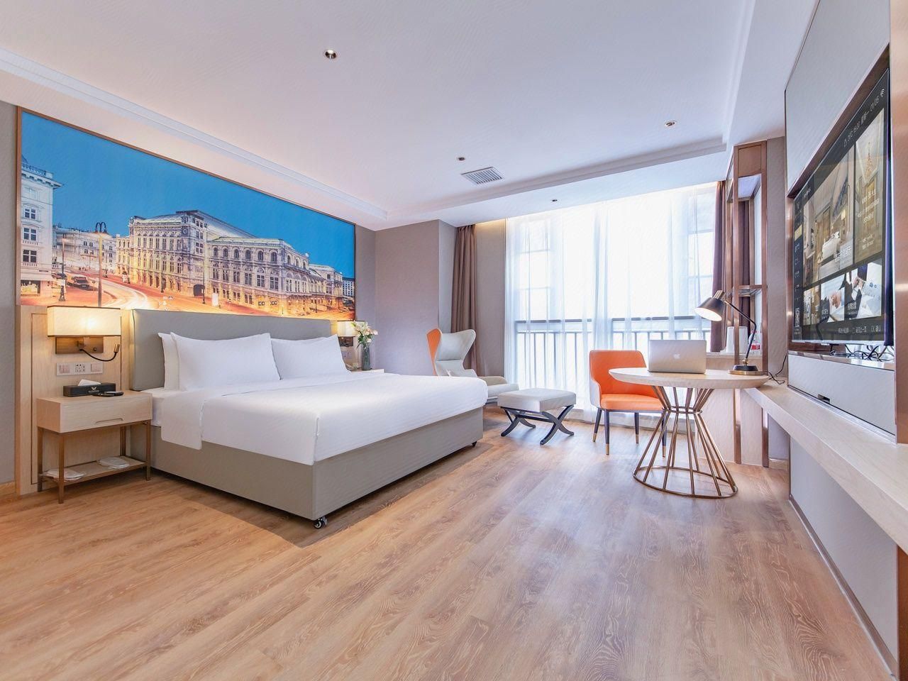 A hotel room with a bed, a desk, a chair, and a large window.