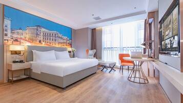 A hotel room with a bed, a desk, a chair, and a large window.