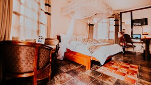 Um quarto com uma cama, uma cadeira, uma escrivaninha e uma televisão.