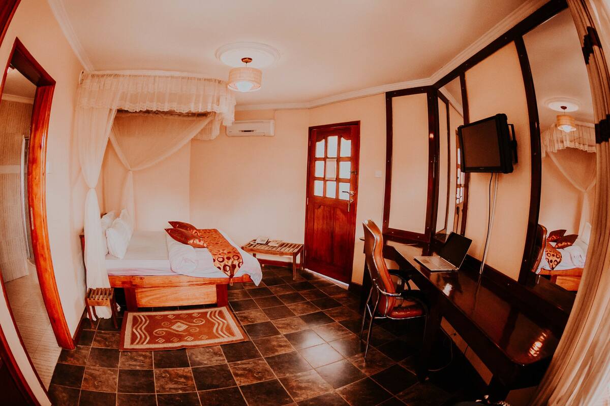 A room with a bed, a desk, a chair, a TV, and a window.
