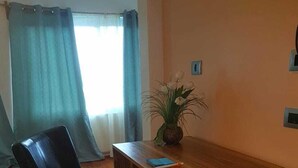 A dining area with a wooden table and a black chair. There is a small potted plant on the table. - West End room (Roatan)