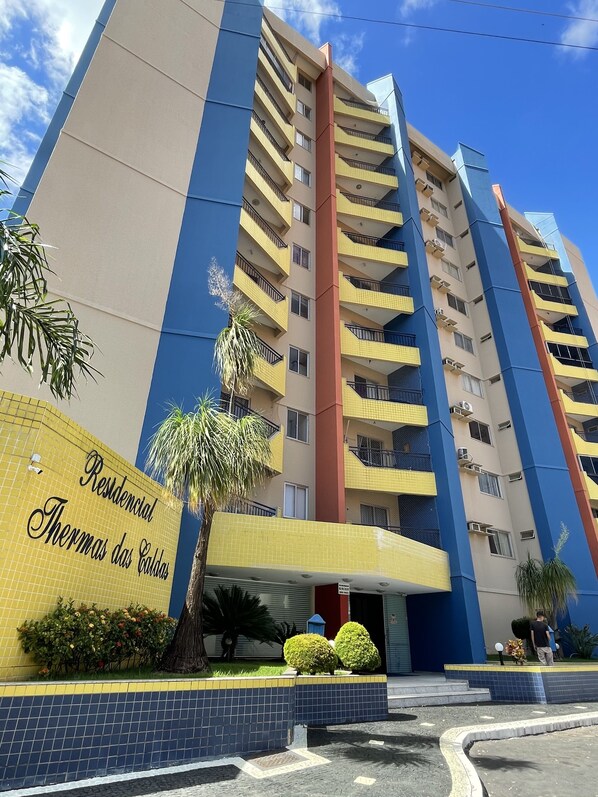 A multi-story residential building with a yellow and blue facade, balconies, and a sign reading "Residencial Thermas das Caldas".