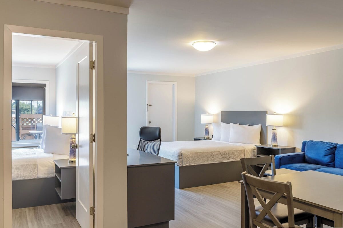 Ein Hotelzimmer mit Bett, Schreibtisch, Stuhl, Sofa und einem kleinen Tisch.
