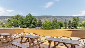 A wooden deck with picnic tables overlooking a mountainous landscape. - Motel 6 Merritt BC (Merritt)