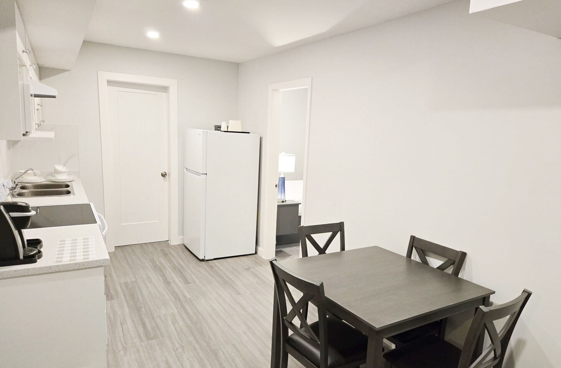 A compact kitchen with a refrigerator, sink, and a dining area with a table and chairs.