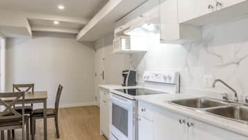 A modern kitchen with white cabinets, a built-in oven, a microwave, and a stainless steel sink.