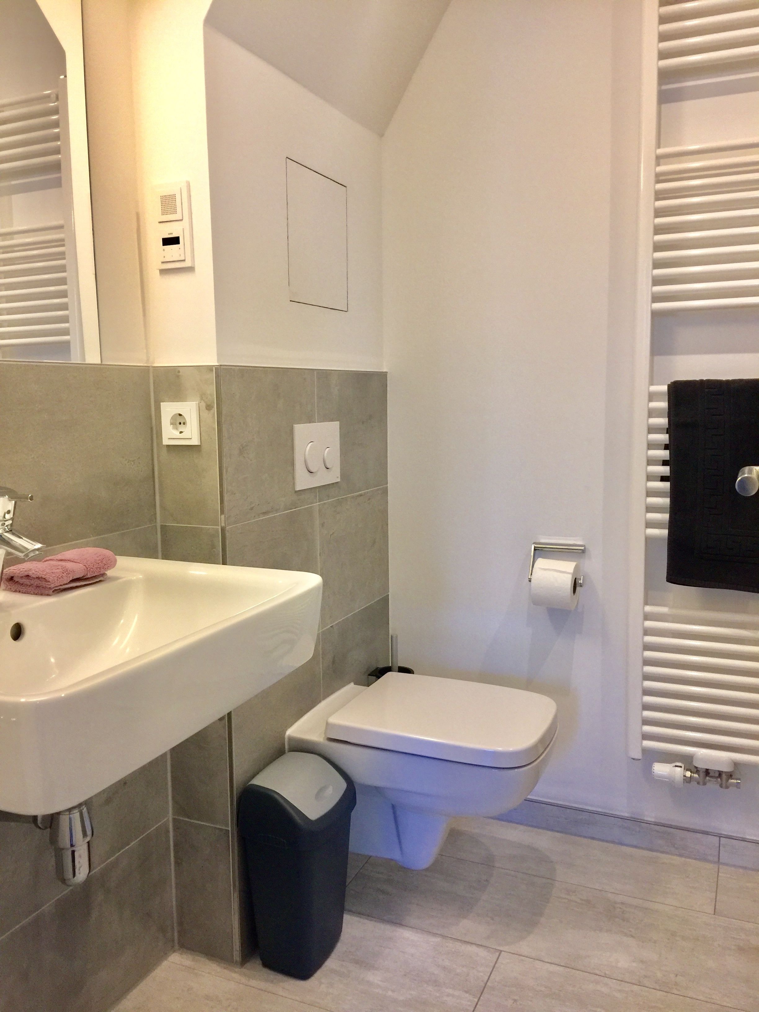A bathroom with a white sink, toilet, and towel rack.
