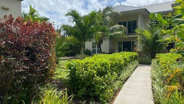 A two-story building with a pathway leading to the entrance. - Anse La Mouche Holiday Apartments (Victoria)