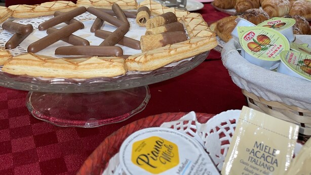 Una mesa de bufé con diversos pasteles, incluyendo una tarta de chocolate y crema, y una cesta de panecillos.