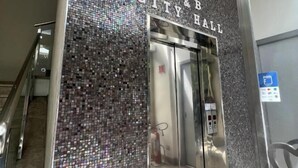 Un ascensor con una pared de mosaicos y un cartel que dice "B&B CITY HALL".