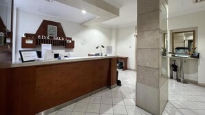 Un mostrador de recepción con encimera de madera, un cartel que dice 'City Hall' y un suelo de baldosas.
