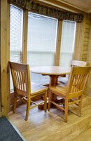 Una mesa de madera para comer con cuatro sillas, frente a una ventana con persianas.