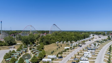 Un camping con vehículos recreativos, una montaña rusa y un cielo azul despejado.