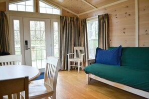 A cozy room with a wooden floor, a green sofa, a white chair, and a dining table. - Worlds of Fun Village (Kansas City)
