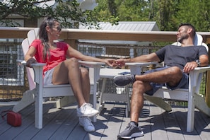 Two people seated on white chairs on a wooden deck, holding hands. - Worlds of Fun Village (Kansas City)