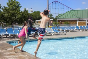 A swimming pool with a water slide and a roller coaster in the background. - Worlds of Fun Village (Kansas City)