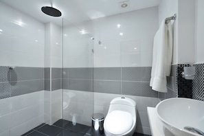 Une salle de bain moderne avec une douche à parois de verre, des toilettes et un lavabo sur pied.