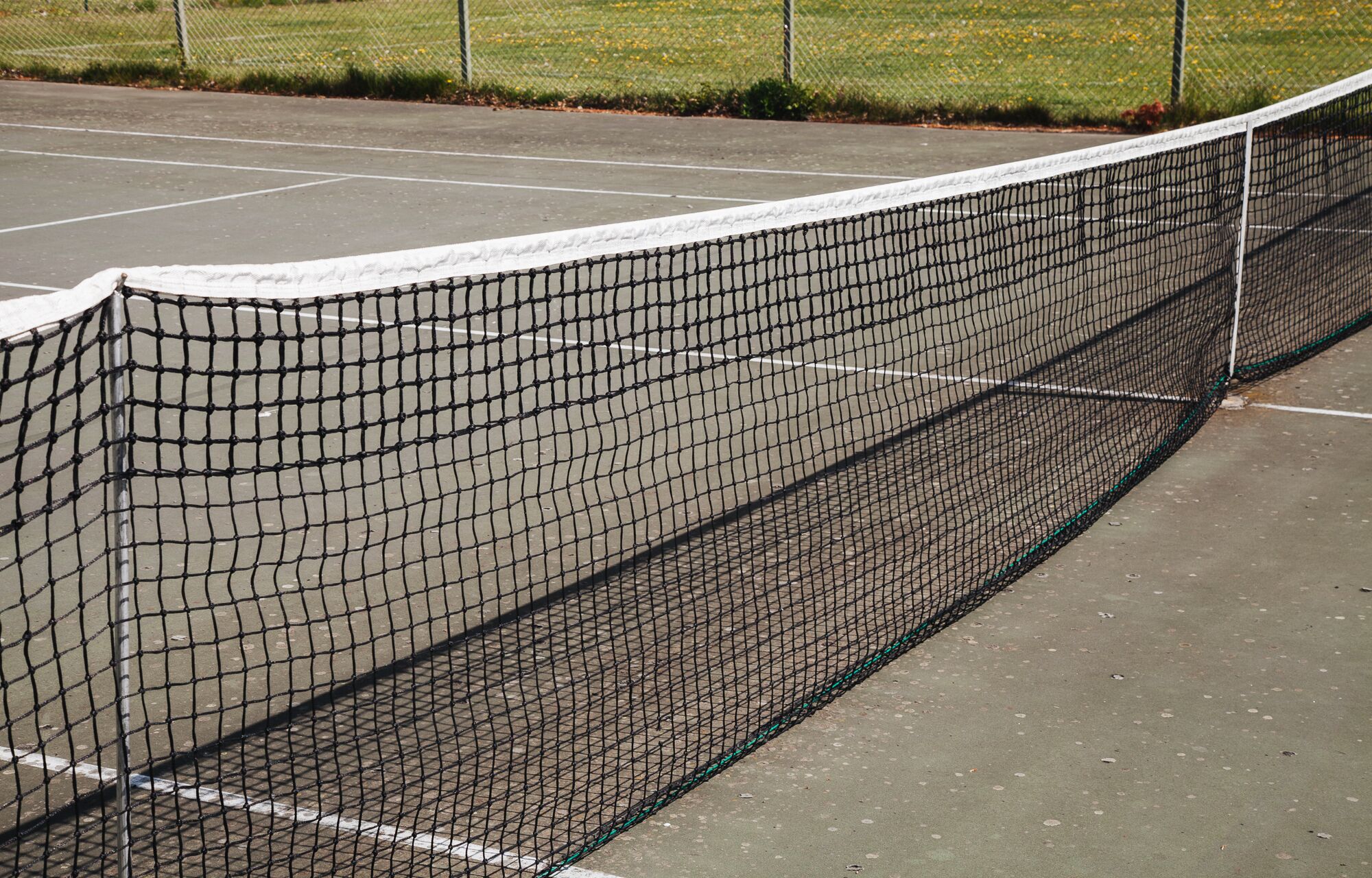 En tennisbana med nät och ett staket runt omkring.
