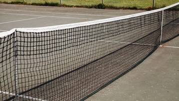 En tennisbana med nät och ett staket runt omkring.
