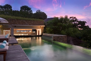 A pool area with lounge chairs and a bar, surrounded by greenery and a stone wall. - The Tamarind Resort Nusa Lembongan Bali (Lembongan Island)