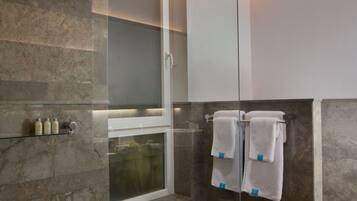 Un baño moderno con cabina de ducha de vidrio, paredes de mármol y puerta de vidrio que da acceso a la zona de ducha.