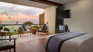 A modern hotel room with a large bed, a TV mounted on the wall, and a balcony with seating and a view of the ocean. - The Tamarind Resort Nusa Lembongan Bali (Lembongan Island)